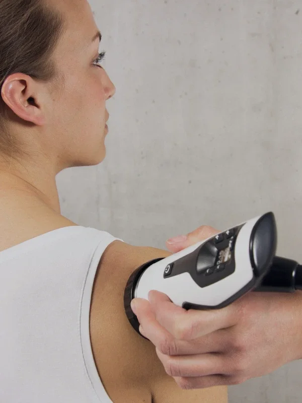 A clinician delivering shockwave therapy to a patient's shoulder